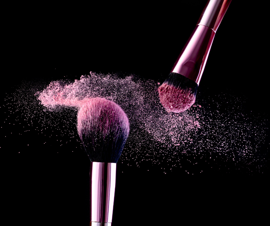 Brocha de maquillaje soltando polvo de color rosa